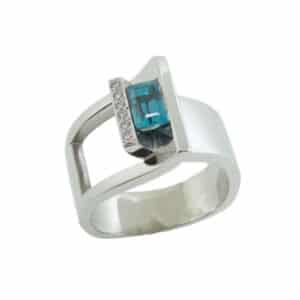 A modern custom designed ring made in 14 karat white gold showcasing a 1.435 carat emerald cut Blue Zircon and accented with round brilliant cut diamonds totaling 0.104 carats. Designed by our jeweler and owner, David Blitt as part of our Studio Tzela line. This fun fashion ring is perfect to represent December birthdays.