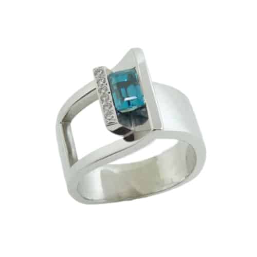 A modern custom designed ring made in 14 karat white gold showcasing a 1.435 carat emerald cut Blue Zircon and accented with round brilliant cut diamonds totaling 0.104 carats. Designed by our jeweler and owner, David Blitt as part of our Studio Tzela line. This fun fashion ring is perfect to represent December birthdays.