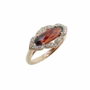 Claw set in an antique 14 karat rose gold design, this ring showcases a 1.75 carat elongated oval shaped Garnet. Accented with a halo of diamonds totaling 0.18 carats.