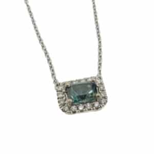 14 karat pendant featuring a stunning 0.622 carat blue/green sapphire and is accented by a halo of 16 round brilliant cut diamonds.