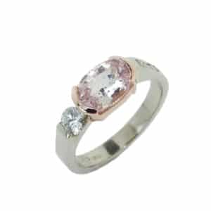 14 karat rose and white gold ring featuring a semi-bezel set 1.31ct oval pink sapphire and accented with 0.262ctw of round brilliant cut diamonds.