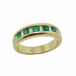 18 karat yellow gold ring channel set with 5 = 0.45ctw princess cut emeralds and 6 = 0.118ctw baguette cut diamonds. Emerald is the birthstone for May.
