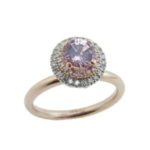 14 karat rose and white gold ring featuring a 0.725ct light pink sapphire accented by a double halo of 0.20ctw round brilliant cut diamonds.