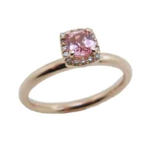 14 karat rose gold ring featuring a 0.40ct Padparadscha sapphire and a halo of round brilliant cut diamonds.