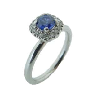 14 karat white gold halo ring set with a 0.469ct sapphire and 0.125ctw, H/I, SI1-2, round brilliant cut diamonds.
