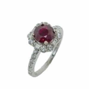 A unique halo ring by Ancora in 14 karat white gold, showcasing a 1.25 carat Ruby. Accented with four baguette cut diamonds totaling 0.18 carats in the halo, among round brilliant cut diamonds totaling 0.50 carats. This ring is a perfect gift to represent July birthdays and 40th anniversaries.