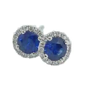 18 karat white gold stud earrings set with sapphires and accented with a halo of diamonds.