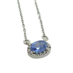 14 karat white gold pendant featuring a 0.388 carat oval blue sapphire and a halo of round brilliant cut diamonds, 0.05 total carat weight. This pendant comes with an 18" chain. Sapphire is the birthstone for September.