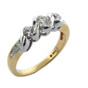 14K yellow and white gold three stone engagement ring by Studio Tzela. Semi-bezel and pave set with ideal cut, round brilliant cut Hearts On Fire diamonds featuring a 0.244ct H, SI1 centre and accented on the sides and band with 0.273 carat total weight Hearts On Fire diamonds, SI1-SI2, G/H.