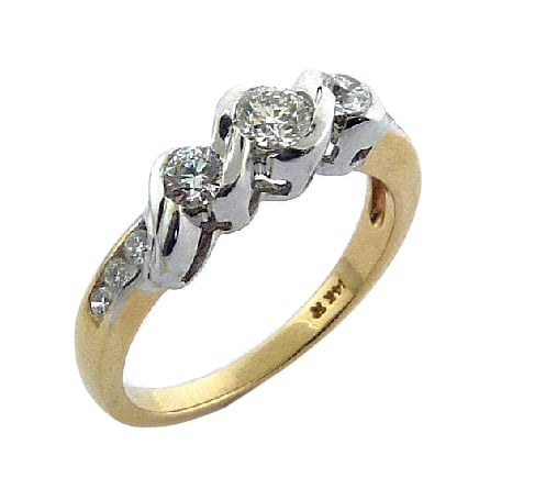 14K yellow and white gold three stone engagement ring by Studio Tzela. Semi-bezel and pave set with ideal cut, round brilliant cut Hearts On Fire diamonds featuring a 0.244ct H, SI1 centre and accented on the sides and band with 0.273 carat total weight Hearts On Fire diamonds, SI1-SI2, G/H.
