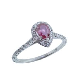 In 14 karat white gold, this halo ring showcases a 0.44 carat pear shaped treated pink diamond set above  bezel set peek-a-boo diamonds. Accented with diamonds totaling 0.37 carats. The perfect gift for 10th anniversaries, 60th anniversaries, April birthdays or a stunning engagement ring!