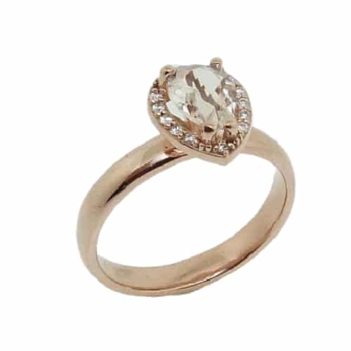 A 14 karat rose gold halo ring, Showcasing a 0.51 carat pear shaped Morganite. Surrounded by diamonds totaling 0.07 carats. A beautifully delicate piece that can be used for an engagement ring or a fun fashion ring.