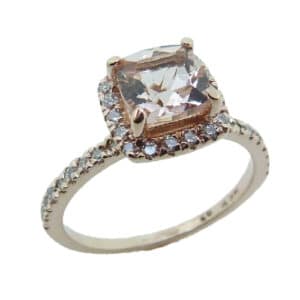 A 14 karat rose gold halo ring, Showcasing a 0.972 carat cushion cut Morganite. Surrounded by diamonds totaling 0.285 carats. A beautifully delicate piece that can be used for an engagement ring or a fun fashion ring.