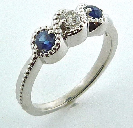 14 karat three stone ring featuring a 0.11ct H/I, SI1-2, round brilliant cut diamond and 2 = 0.30ct round sapphires.