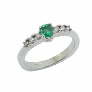 14 karat white gold ring set with a 0.27 carat oval emerald and accented with six round brilliant cut diamonds, 0.142 total carat weight, G/H, SI. Emerald is the birthstone for May.