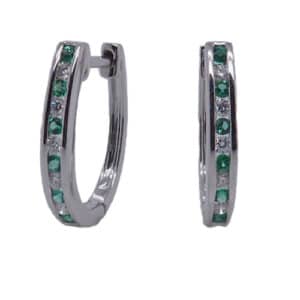 14 karat white gold hoop earrings channel set with 0.14ctw of emeralds and 0.13ctw G/H, SI round brilliant cut diamonds. Emerald is the birthstone.