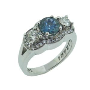 14 karat white gold ring featuring a 1.00ct Montana blue/green sapphire accented by 2 = 0.483ct, ideal cut, I, SI, round brilliant cut diamonds and a halo of 30 = 0.25cttw G/H, SI. Sapphire is the birthstone for September.