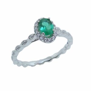 Lady's scalloped edge band ring with milgrain detail in 14K White gold, set in the halo with one 0.36 carat oval emerald and accented with twenty-six G-H, SI1-2 round brilliant cut diamonds totaling 0.12 carats.