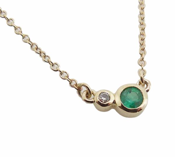 14K yellow gold pendant bezel set with a 0.09ct Emerald and a 0.014ct G/H, I1 round brilliant cut diamond.  Emerald is the birthstone for May.