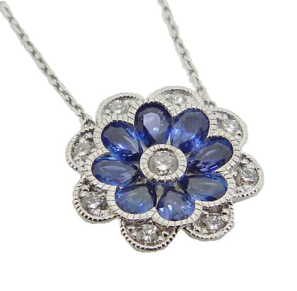 14K white gold floral inspired pendant on a chain set with nine round brilliant cut diamonds, 0.25cttw, G/H, SI, very good cut and eight pear shape blue sapphires, 1.49cttw.