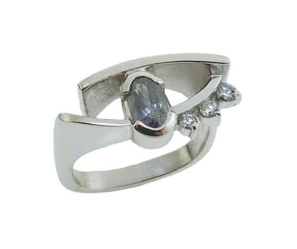Lady's white gold custom ring semi bezel set with one 0.85 carat oval Alexandrite and claw-set with three F-G, SI+ excellent cut round brilliant cut diamonds, totaling 0.113 carats.