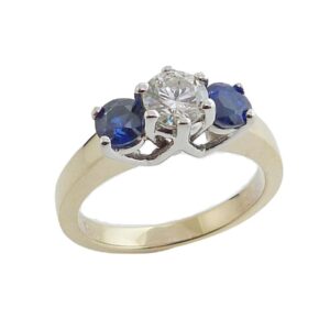 14K White and yellow gold engagement ring claw set with a 0.51 carat I, I1 very good cut, round brilliant cut diamond and accented on each side with two round blue sapphires, totalling 0.98 carat.
