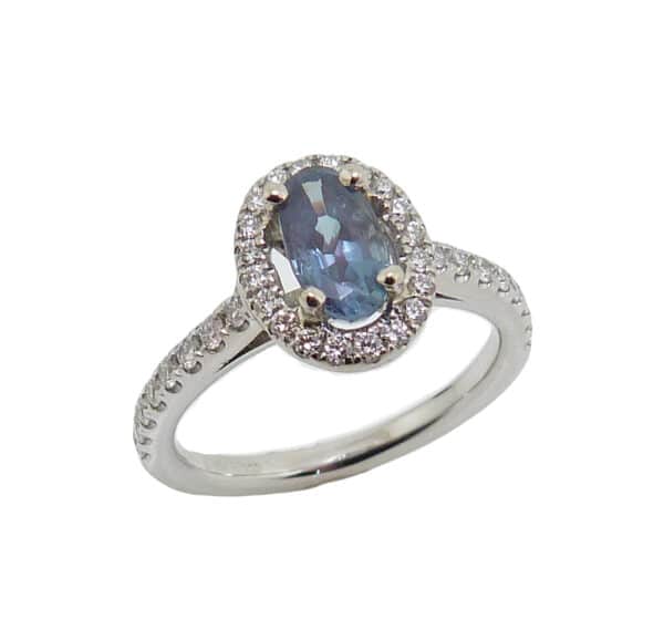 19 karat white gold halo style ring set with a 0.79ct Alexandrite and accented with 0.32cttw G/H, SI1-2, very good cut, round brilliant cut diamonds. Alexandrite is the birthstone for June.