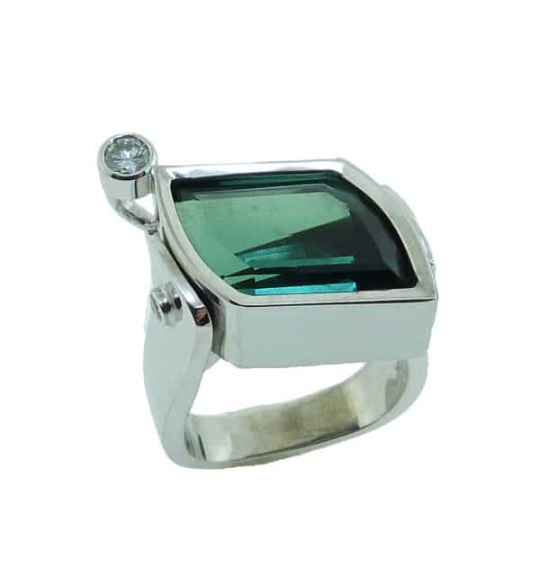 19 karat white gold coloured gemstone ring by Studio Tzela bezel set with one 7.90 carat Green Tourmaline and accented with a round brilliant cut diamond, 0.14 cttw, SI2, H/I and 2 bezel set round brilliant cut diamonds, 0.04cttw, SI.