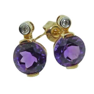 Lady's 14K yellow gold amethyst earrings, set with two round 6.5-7mm amethysts and accented with two small diamonds totaling 0.02 carats.
