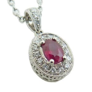 Lady's 18K white gold pendant set with one 0.56 carats oval ruby and accented with round brilliant cut diamonds totaling 0.20 carats.