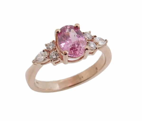 14 karat rose gold ring featuring a 1.25ct Padparadscha sapphire, 4 = 0.12cttw round brilliant cut diamonds, 2 = 0.13cttw pear shape diamonds. 