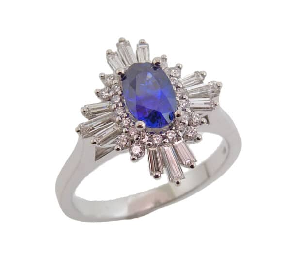 Lady's 14K white gold custom halo ring set with one 0.937 carat oval blue sapphire and accented with twelve baguettes totaling 0.42 carats, G-H, VS and twenty-six round brilliant cut diamonds totaling 0.18 carats, F-G, VS.