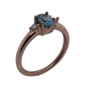14 Karat rose gold lady's coloured gemstone ring set with an oval brilliant cut blue zircon, 0.747 carat, and accented with two round brilliant cut diamonds totaling 0.065 carats, SI, H/I.
