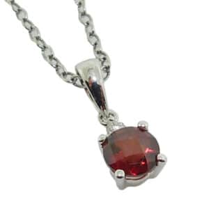 14K White gold pendant set with a round checkerboard cut red garnet, 0.50 carat, and accented with a 0.02 carat round brilliant cut diamond.
