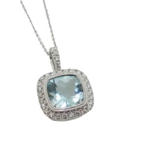 14 Karat white gold halo pendant with milgrain detail bezel set with one 1.24 carat cushion cut aquamarine and claw set in the halo with thirty round brilliant cut diamonds, totaling 0.18 carats, G/H, SI-VS. This pendant comes with a 16" 14K white gold cable chain.