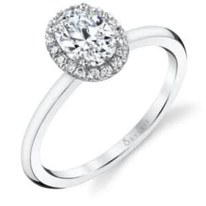 14 Karat white gold engagement ring "Elsie" by Sylvie Collection. Set with a 0.75 carat oval CZ and with round brilliant cut diamonds on the halo totaling 0.12 carats, G/H, VS-SI. Available in 14K gold, 18K gold, or platinum. This ring can be made in any combination of white, pink or yellow gold and can be customized to accommodate different size and shape diamonds, by special order. Priced without a center gemstone. Let us find you the perfect center that fits your tastes and budget!