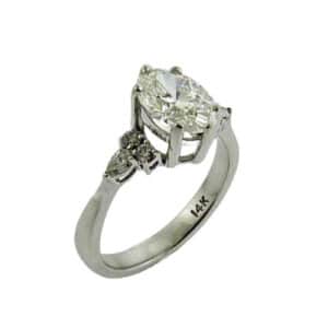 14 Karat white gold engagement ring set with one 1.42 carat lab grown oval diamond, D, VS1. Accented with two pear shaped natural diamonds totaling 0.13 carats, very good cut, SI1-VS2, G and four round brilliant cut natural diamonds totaling 0.12 carats, very good cut, SI1-VS2, F/G. Available in 14K gold, 18K gold, or platinum. This ring can be made in any combination of white, pink or yellow gold and can be customized to accommodate different size and shape diamonds, by special order.
