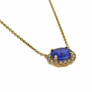 Lady's 14K yellow gold necklace set with 1.2 carat (7x5) oval blue sapphire and accented with 16 round brilliant cut diamonds totaling 0.12 carats.