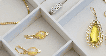 yellow gemstone earrings and a necklace and ring arranged in boxes