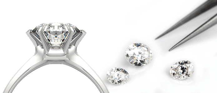silver engagement ring in front of loose diamonds and tweezers