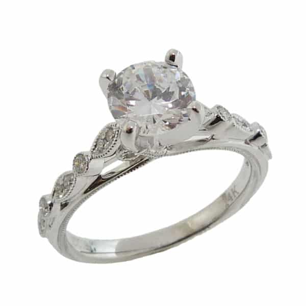 14K White gold engagement ring with milgrain scalloped edge and profile details set in the centre with a 1.0 carat CZ and on the band with 16 pave set round brilliant cut diamonds, 0.14cttw. Available in 14K gold, 18K gold, or platinum. This ring can be made in any combination of white, pink or yellow gold and can be customized to accommodate different size and shape diamonds, by special order. Priced without a center gemstone. Let us find you the perfect center that fits your tastes and budget!