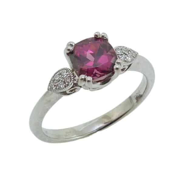 14K White gold ring set with 6x6 mm cushion rhodolite garnet and accented with 10 round brilliant cut diamonds totaling 0.06 carats.