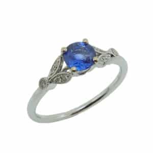 14K White gold lady's ring with  milgrain detail set in the centre with 0.68 carat sapphire and accented on each side with pave and bezel set round brilliant cut diamonds, 0.05 total carat weight.