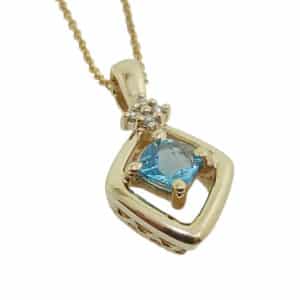 14K yellow gold pendant set with a 0.69 carat blue topaz and accented with 4 round brilliant cut diamonds totaling 0.034 carats, H, SI1-2.