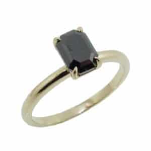14K Yellow gold solitaire engagement ring set in the centre with a 1.261 carat emerald cut black diamond.