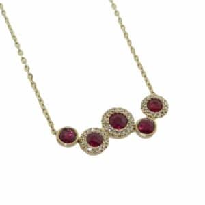 14K Yellow gold halo and bezel set ruby necklace set with 5 rubies, 0.47 total carat weight, and 44 round brilliant cut diamonds, 0.08 total carat weight.