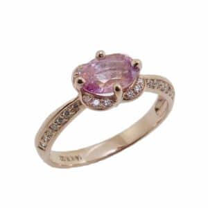 14K Rose gold unique halo lady's ring horizontally set with a 1.10 carat oval Padparadscha sapphire and accented on the halo and band with natural round brilliant cut diamonds, 0.164 total carat weight, G/H, SI1-2.