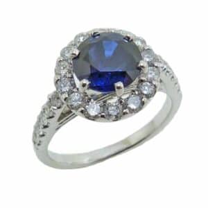 14K White gold lady's halo ring claw set in the centre with a 2.16 carat round, heat treated, blue sapphire and accented on the halo and band with very good cut, round brilliant cut diamonds, 0.60 total carat weight, G/H, SI1-2.