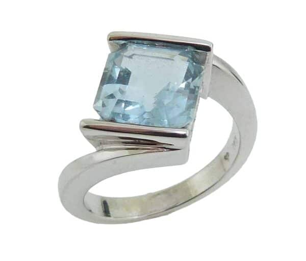 14K White gold custom lady's ring channel set with a 3.27 carat asscher cut aquamarine and accented on the profile with 10 pave set very good cut, round brilliant cut diamonds, 0.04 total carat weight, G/H, SI.