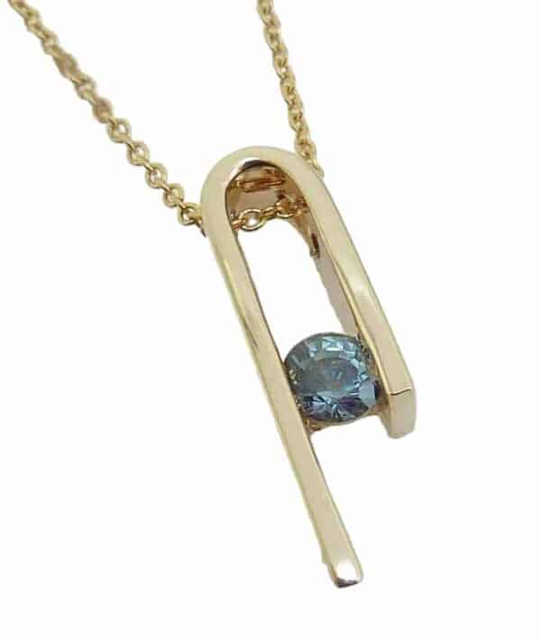14K Yellow gold custom pendant by Studio Tzela channel set with a 0.392 carat teal sapphire.